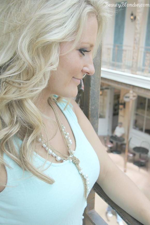 Long Blonde Curly Hair with a Mint Top and a Mint and Gold Necklace